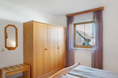 a bedroom with a wooden cabinet and a window at Ferienwohnungen Hackerhof in Bad Füssing