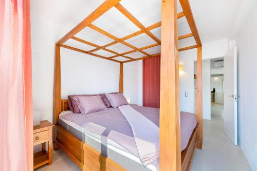 a bedroom with a canopy bed with purple pillows at Casa Rewa in Port d'Alcudia