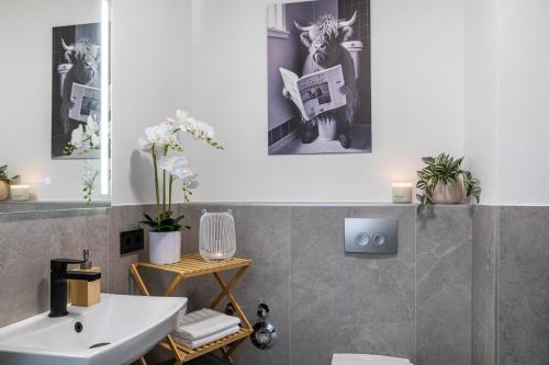 a bathroom with a sink and a toilet and some pictures at Marktplatz Ferienwohnung in Alsfeld