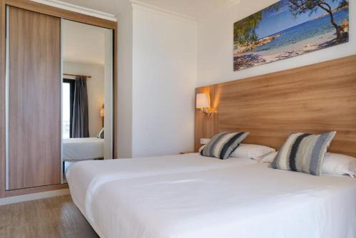 a hotel room with a large white bed and a mirror at R2 Cala Millor in Cala Millor