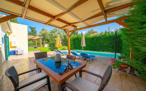 a patio with a table and chairs and an umbrella at Sami Beach Villas Dafni in Sami