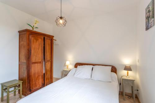 a bedroom with a white bed and a wooden cabinet at Maison de vacances Camille in Artigues