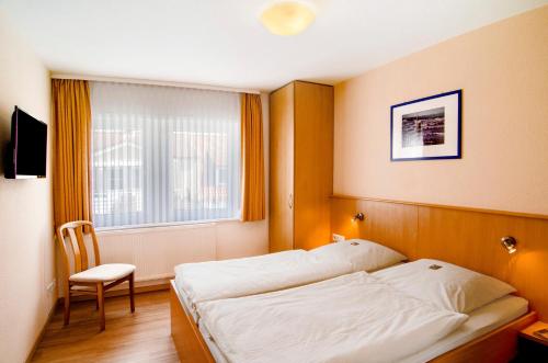 a bedroom with a bed and a chair and a window at Huus Nördernee 1 in Norderney
