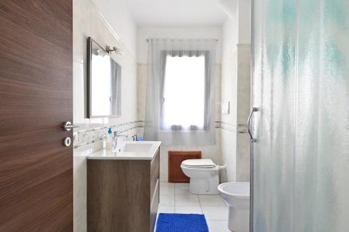 a bathroom with a sink and a toilet and a window at Casa Spaziosa in Bari Sardo