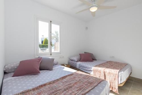 a bedroom with two beds and a window at Chalet a 150m de la playa y piscina privada in Cala en Bosc