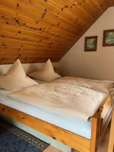 a large bed in a room with a wooden ceiling at Gästehaus Schoch-Bächle in Bad Rippoldsau-Schapbach