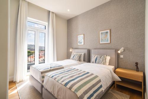 a bedroom with two beds and a large window at Solar do Ilheuzinho in Câmara de Lobos