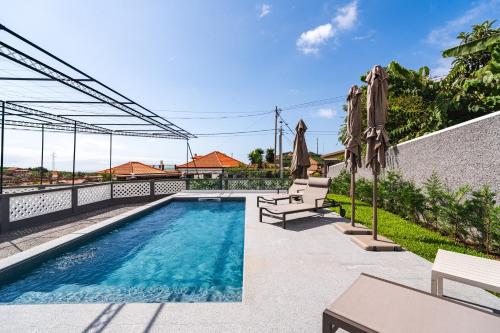 a swimming pool with umbrellas next to a building at Solar do Ilheuzinho in Câmara de Lobos