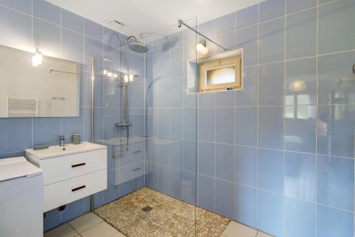 a blue tiled bathroom with a sink and a mirror at La Cense De La Mérelie - Le Logis in Saint-Geniès