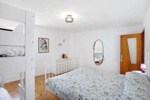 a white bedroom with a bed and a mirror at da Lule in Aosta
