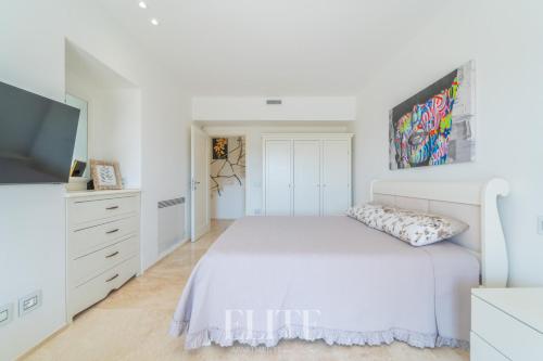 a white bedroom with a bed and a flat screen tv at Elite Collection Villa Noemi in Porto Rotondo