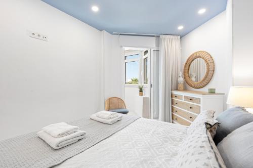 a white bedroom with a bed and a mirror at Plazamar 044 in Torre del Mar
