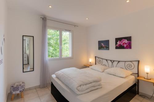a bedroom with a bed with white sheets and a window at Le Pequelet in Payzac