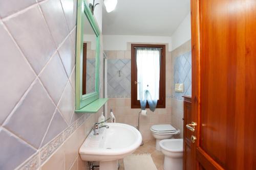 a bathroom with a sink and a toilet and a mirror at Appartamento Melissa a Orosei in Orosei