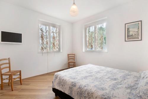 a white bedroom with a bed and two windows at Villa Angelina in Lavagna