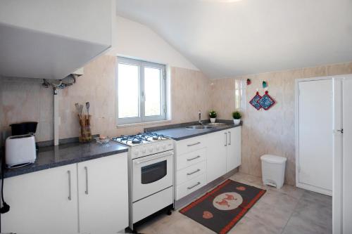 a kitchen with white cabinets and a stove top oven at Quinta das Andorinhas - Nazaré in Famalicão