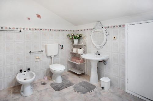 a bathroom with a sink and a toilet and a mirror at Quinta das Andorinhas - Nazaré in Famalicão