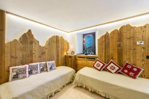 two beds in a room with wooden walls at Il Nido di Letizia in Châtillon