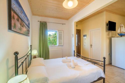 a bedroom with a bed with white sheets and a window at Captain Spiros Picola in Gaios