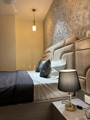 a bedroom with a bed with a headboard and a lamp at The Bloomhouse inn in Rājpur