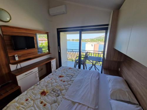 a bedroom with a bed and a television and a balcony at Pansion Croatia in Starigrad