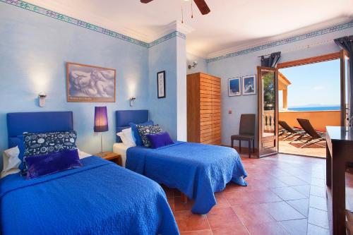 a blue bedroom with two beds and a balcony at Villa Juan Carlos in Cala Vinyes