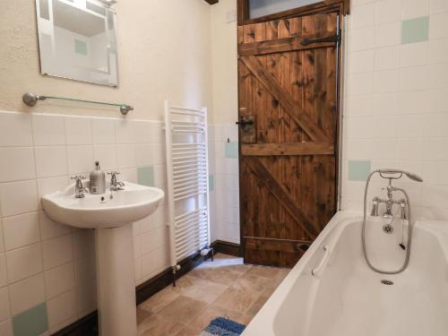 a bathroom with a sink and a bath tub and a wooden door at Cider Cottage - near Lyme Regis in Axminster