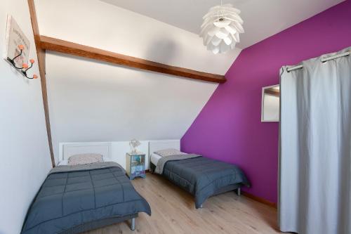 a room with two beds and a purple wall at Gite Les Salicornes in Lanchères