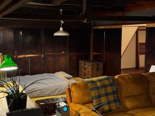ein Wohnzimmer mit einem Bett und einer Couch in der Unterkunft MEKIKI古民家 yorimichi in Yamanashi