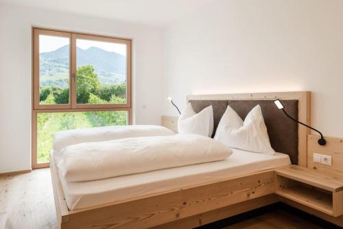 a white bedroom with a large bed with a window at Natur Suite Edelweisshof App Heidi in Chiusa