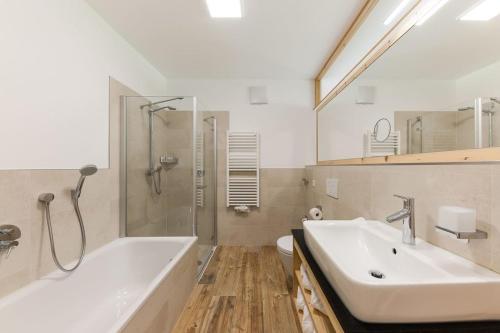 a bathroom with a sink and a tub and a toilet at Natur Suite Edelweisshof App Heidi in Chiusa