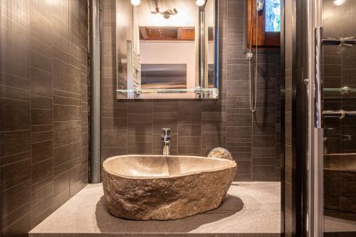 a large stone tub in a bathroom with a mirror at Appartement Les Cezares in Les Allues