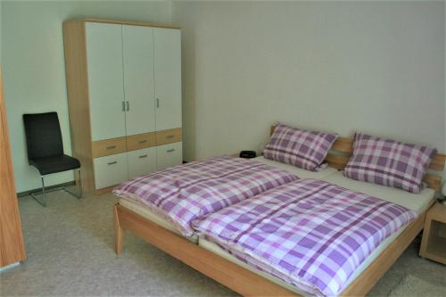 a bedroom with a bed with a dresser and a chair at Haus am Waldrand in Triberg