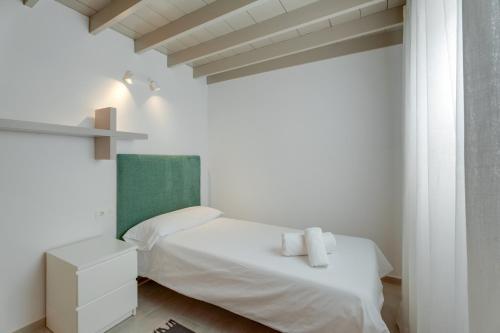 a white bedroom with a bed and a cross on the wall at Serenity in Arona