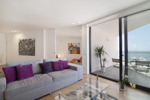 a living room with a couch and purple pillows at Mare Nostrum in Olhão