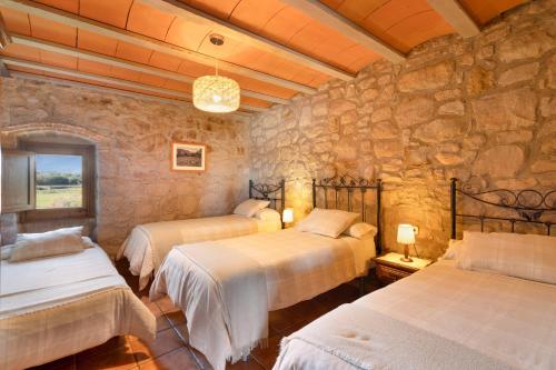 a bedroom with two beds and a stone wall at Cal Cirera in Sagás