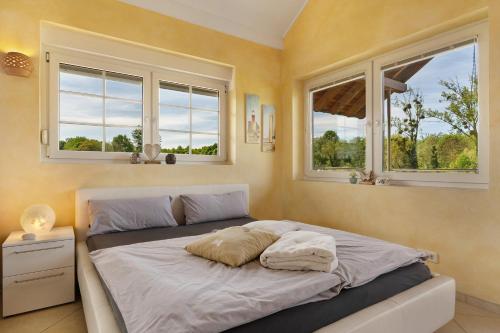 a bed in a bedroom with two windows at Gästesuite mit Sauna in Kehl am Rhein