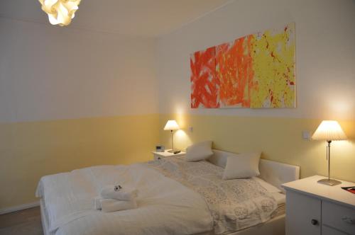 a bedroom with a white bed with two lamps and a painting at Ferienwohnung Harz Idylle in Güntersberge