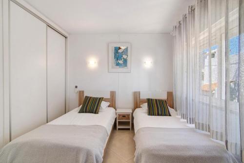 two beds in a room with a window at Townhouse Ramas in Vale do Lobo