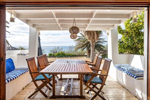 an outdoor patio with a wooden table and chairs at Casa da Praia in Vila Baleira