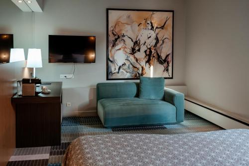 a hotel room with a blue chair and a tv at Hotel Derlon in Maastricht