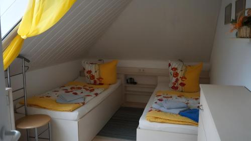 two beds in a small room with yellow curtains at Fewo Hiddensee, 2 Personen 40 M² in Wiek auf Rügen