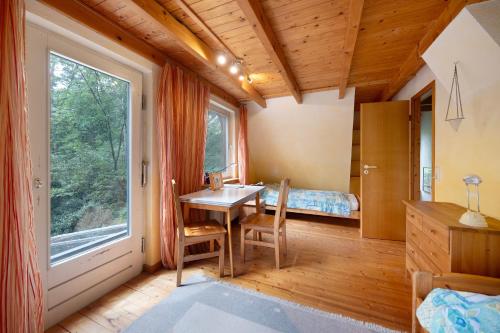 a room with a table and a bed and a window at Ferienhaus am Brandorffsee in Wiefelstede