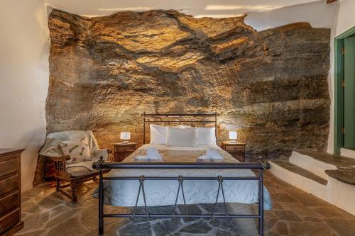 a bedroom with a bed in a stone wall at Traditional Olive Guesthouse in Fállika