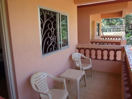 einen Balkon mit weißen Stühlen und einem Fenster in der Unterkunft Empire Guest House in Calangute