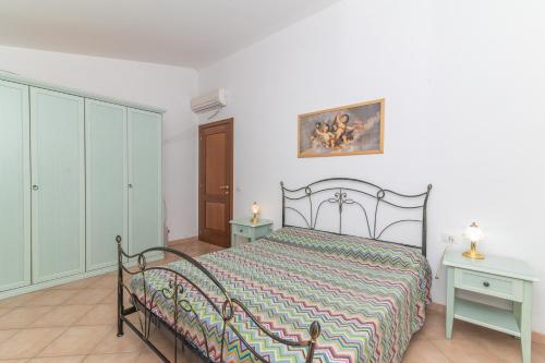 a bedroom with a bed and two tables and a picture on the wall at Villa San Teodoro in Nuragheddu