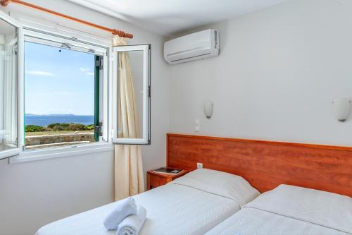 a bedroom with a bed and a window at Anemologio 101 Tinos in Agios Ioannis