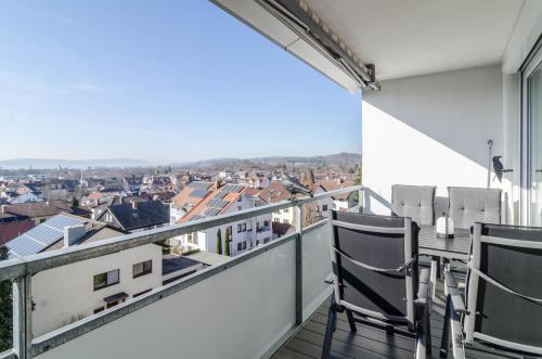 a balcony with chairs and a view of a city at Bodenseepanorama Oberuhldingen in Uhldingen-Mühlhofen