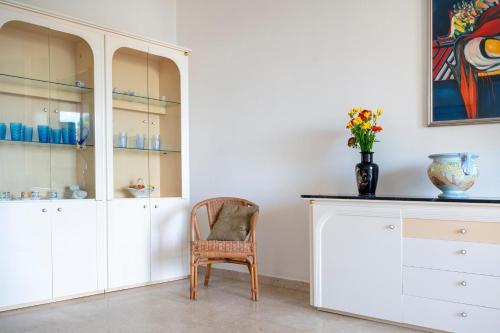a room with white cabinets and a chair and a vase at Stella Vacanze in Otranto