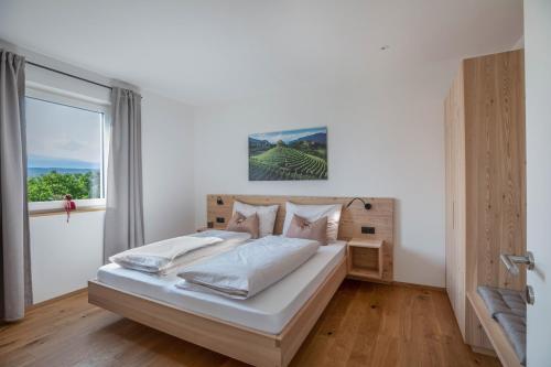 a bedroom with a large white bed with a window at Meine Bleibe Apartment Terra in Appiano sulla Strada del Vino